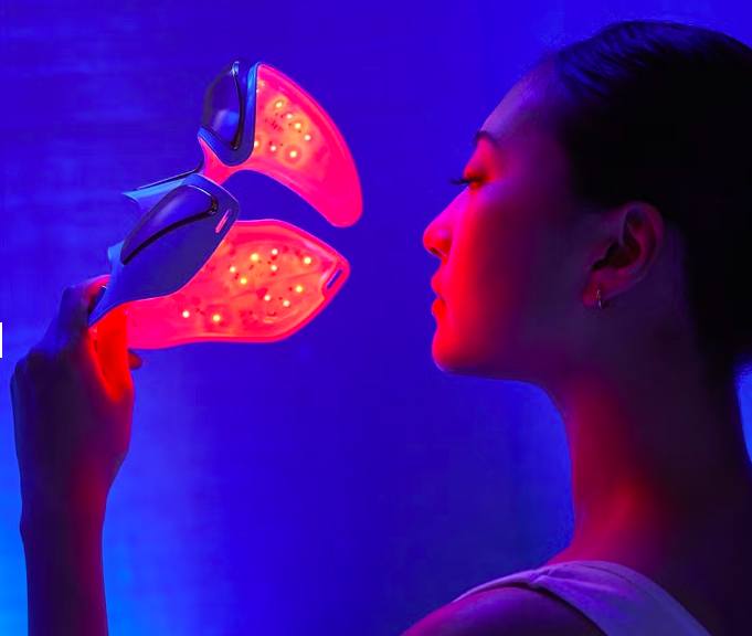 Woman holding a red and blue LED light therapy face mask